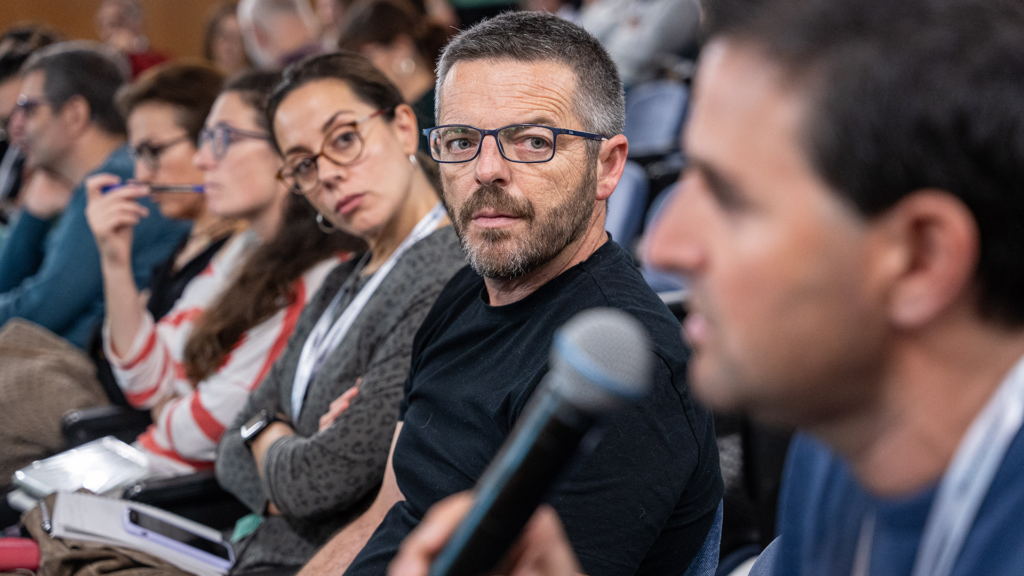 Un asistente interviene desde su butaca ante la atenta mirada del resto de asistentes.